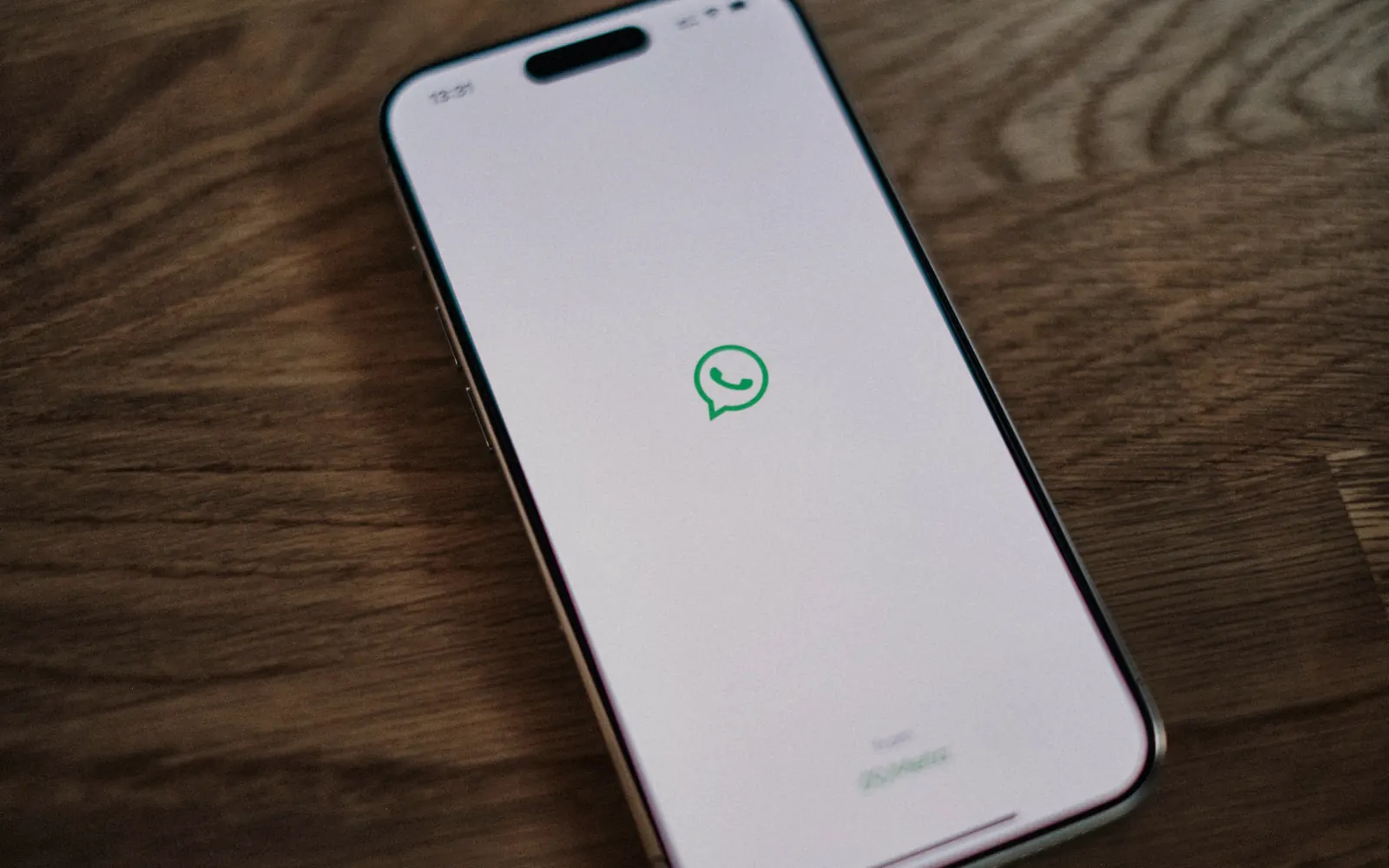 Smartphone showing a WhatsApp message on a wooden desk